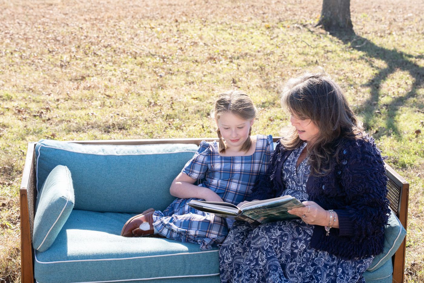 A woman and a child reading together outdoors